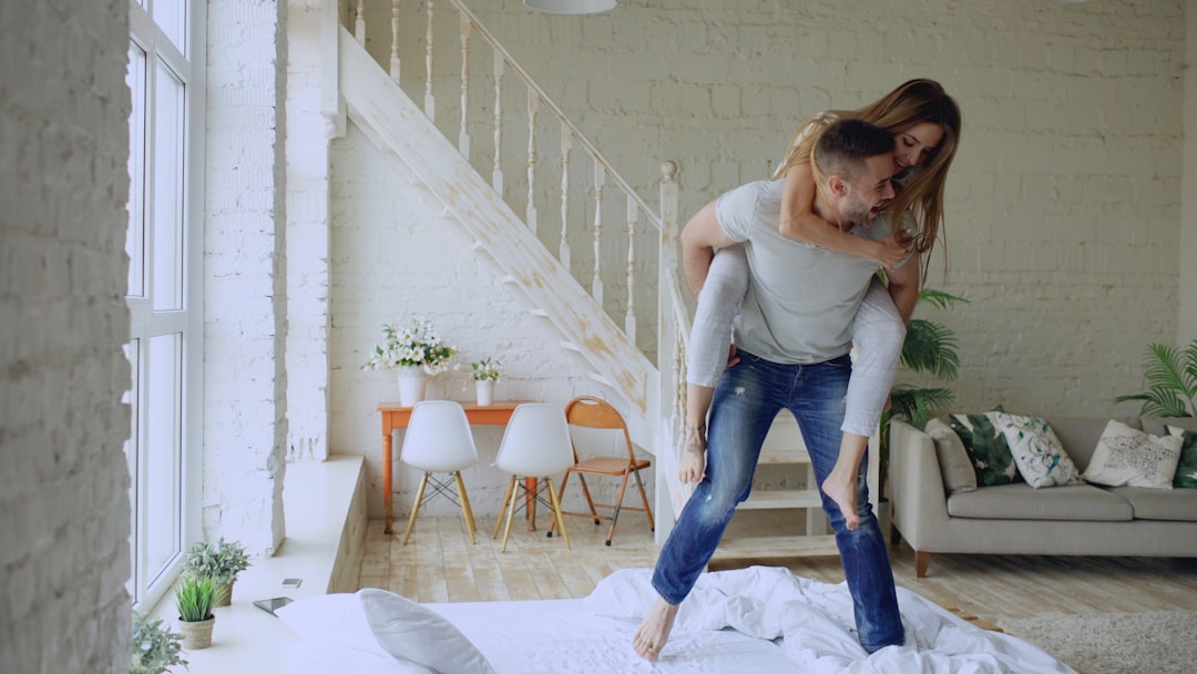 beautiful and loving couple dancing while having piggyback ride on bed in the morning at home